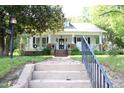Inviting front porch with black door, decorative wreath, black railings, and brick stairs and posts at 1111 College St, Oxford, NC 27565