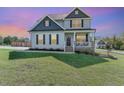 Charming two-story home with a welcoming front porch and well-manicured lawn and stylish landscaping at dusk at 1302 Reading Ct, Burlington, NC 27217