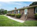 Brick home with stairs leading to front door, black shutters, and manicured bushes at 201 E Laramie Dr, Mebane, NC 27302