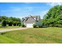 Landscaped yard with a traditional home, two-car garage and long drive under a blue sky at 2062 Montgomery Dr, Franklinton, NC 27525