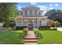 Inviting two-story house with a spacious porch, landscaped front yard, and brick pathway at 207 N Hopkins Ave, Spring Hope, NC 27882