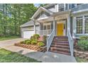 Up close view of a charming home with a yellow front door, lush landscaping, and a brick staircase at 2513 Myrtle Ln, Hillsborough, NC 27278