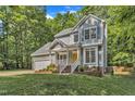 Two-story home with gray siding, lush landscaping and a bright yellow front door surrounded by mature shade trees at 2513 Myrtle Ln, Hillsborough, NC 27278