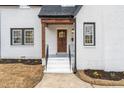 Charming front entrance with a wood door, white brick, and landscaped flower beds at 2515 W Club Blvd, Durham, NC 27705