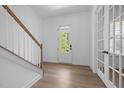 Bright foyer featuring wood-look floors, white walls, and a staircase with a wooden handrail at 386 The Parks Dr, Pittsboro, NC 27312