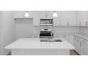 Modern kitchen featuring stainless steel appliances, white cabinets, subway tile backsplash, and a spacious quartz countertop island at 425 Providence Springs Ln, Fuquay Varina, NC 27526