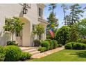 Home's entry with professionally landscaped yard, trees, stone pathway and American flag in background at 4404 Yadkin Dr, Raleigh, NC 27609