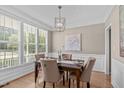Elegant dining room featuring hardwood floors, modern chandelier, and wainscoting detail, flooded with natural light at 6002 Whisperwood Dr, Durham, NC 27713