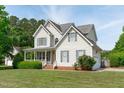 Beautiful two-story home with a well-manicured lawn, side-entry garage, and charming architectural details at 6002 Whisperwood Dr, Durham, NC 27713