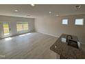 Open concept living room showcasing a kitchen island, modern lighting, and access to the backyard at 67 Commons Cir, Clayton, NC 27520