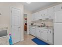 Functional kitchen features white cabinets and appliances, plus durable tile flooring at 704 Benchmark Dr, Raleigh, NC 27615