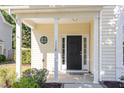 Charming front porch featuring classic columns and a black front door with sidelights at 1148 Dexter Ridge Dr, Holly Springs, NC 27540