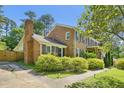 Side view of brick house with shutters, chimney, mature trees, and manicured shrubs at 1315 Brigham Rd, Chapel Hill, NC 27517
