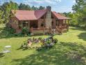 Aerial view showcasing a log cabin home with a stone chimney, front porch, water garden, and lush yard at 1656 Nc-42 Hwy, Moncure, NC 27559