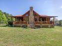 Exterior showcasing a log cabin home with a stone chimney, front porch, and lush yard at 1656 Nc-42 Hwy, Moncure, NC 27559