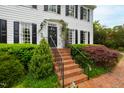 Close-up of home's entrance featuring brick steps, black railings, and meticulously maintained landscaping at 1904 Victoria Rd, Raleigh, NC 27608