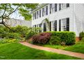 Charming home with brick walkway, lush landscaping, mature trees, and a well-maintained green lawn at 1904 Victoria Rd, Raleigh, NC 27608