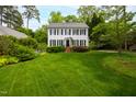 Classic two-story home with black shutters and a well-manicured green lawn surrounded by mature trees and shrubs at 1904 Victoria Rd, Raleigh, NC 27608