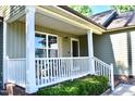 Inviting front porch featuring white railing, brick foundation, and a cozy seating area at 1980 Ferbow St, Creedmoor, NC 27522