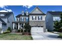 Charming home features a brick facade, covered porch, and an attached two car garage at 232 Hensley Hill Pl, Holly Springs, NC 27540