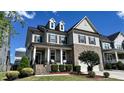 Two-story home featuring a welcoming porch, brick accents, well-manicured lawn, and dormer windows at 232 Hensley Hill Pl, Holly Springs, NC 27540