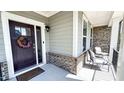 Inviting front porch with comfortable seating, stylish decor, and an elegant entrance door with sidelights at 232 Hensley Hill Pl, Holly Springs, NC 27540