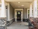 Inviting front porch with stone pillar bases, and a modern front door with sidelights at 325 Avery Glenn Way, Fuquay Varina, NC 27526
