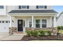 Inviting front porch with stone accents, white columns, and a decorative wreath on the black front door at 4718 Sleepy Falls Run, Knightdale, NC 27545