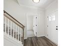 Bright foyer featuring hardwood floors, a staircase with white railings, and an open doorway at 50 Rosewood Ln, Youngsville, NC 27596