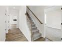 Carpeted staircase with wooden banister and white risers, open to a room with hardwood floors at 50 Rosewood Ln, Youngsville, NC 27596