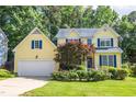 Charming yellow two-story home with blue shutters, a well-manicured lawn, and attached two-car garage at 5417 Harrington Grove Dr, Raleigh, NC 27613