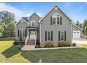 Well-maintained two-story home with charming curb appeal, featuring a brick-lined entryway and lush landscaping at 6200 Oliver Creek Pkwy, Holly Springs, NC 27540