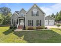 Inviting two-story home with a classic facade, landscaped front yard, and detached two-car garage at 6200 Oliver Creek Pkwy, Holly Springs, NC 27540