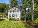 View of a charming two-story home with light-green siding and dormer windows surrounded by mature trees at 6420 Dresden Ln, Raleigh, NC 27612
