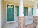 Welcoming covered front porch with a green door and brick accents at 649 Flaherty Ave, Wake Forest, NC 27587