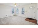 Light-filled living room featuring windows, neutral carpet, and a white front door at 649 Flaherty Ave, Wake Forest, NC 27587