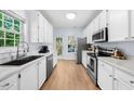 Well-lit kitchen with stainless steel appliances and white cabinets at 6612 Rossford Ln, Durham, NC 27713