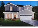 Charming two-story home featuring gray siding, black shutters, a two-car garage, and professionally landscaped flower beds at 712 Deschutes Dr, Garner, NC 27529