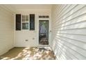 Covered front porch with storm door and adjacent window with black shutters at 8253 Martello Ln, Raleigh, NC 27613