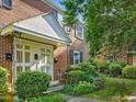 Inviting brick townhouse featuring a covered entrance, manicured landscaping and black window shutters at 945 St Marys St, Raleigh, NC 27605
