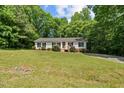 A charming single-story home nestled among lush trees and greenery with a sprawling front lawn at 1004 Candlewood Cir, Siler City, NC 27344