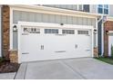 The two car garage door is white and sports black iron hardware at 101 Rostova Way, Holly Springs, NC 27540