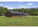 Ranch-style brick home with a well-maintained lawn and mature trees, showcasing its serene setting at 137 Vaiden Rd, Louisburg, NC 27549