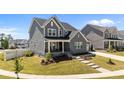 Beautiful gray home with a covered porch, landscaped yard, and a paved walkway leading to the entrance at 236 Artisan Park Dr, Wake Forest, NC 27587