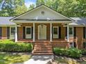 Close up of the front porch featuring brick steps, white columns and manicured bushes at 3204 Manor Ridge Dr, Raleigh, NC 27603