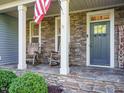 Inviting front porch with stone detailing, rocking chairs, and a welcome sign at 49 Mount Joy Pl, Sanford, NC 27330
