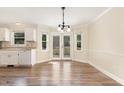Bright dining room with French doors leading to the backyard, complemented by modern chandelier and laminate flooring at 6225 Jones Farm Rd, Wake Forest, NC 27587