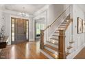 Grand foyer with hardwood floors, elegant staircase, and a stylish chandelier above the front door at 6502 New Market Way, Raleigh, NC 27615