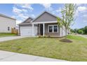 Charming single-Gathering home with a manicured lawn and a young tree in the front yard at 680 Winesap Dr, Graham, NC 27253