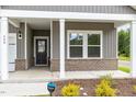 Close-up of a cozy front porch with brick accents, white columns, and a SimpliSafe security sign at 680 Winesap Dr, Graham, NC 27253